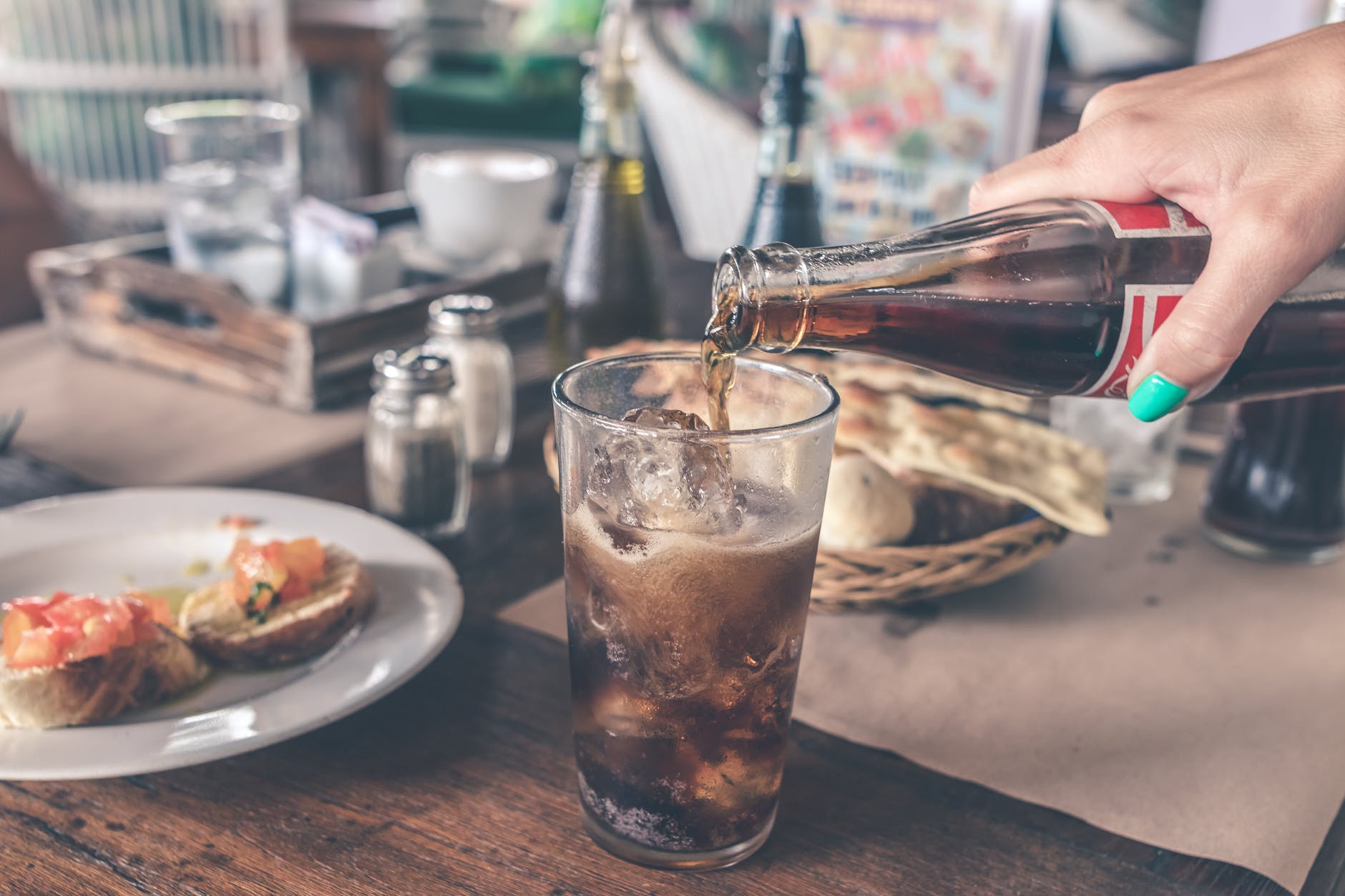 photo of cola pouring into a glass with ice cubes